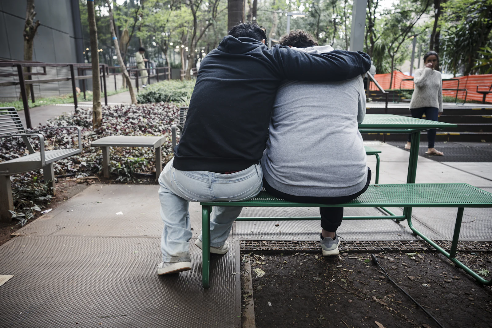 One person comforting another on a park bench